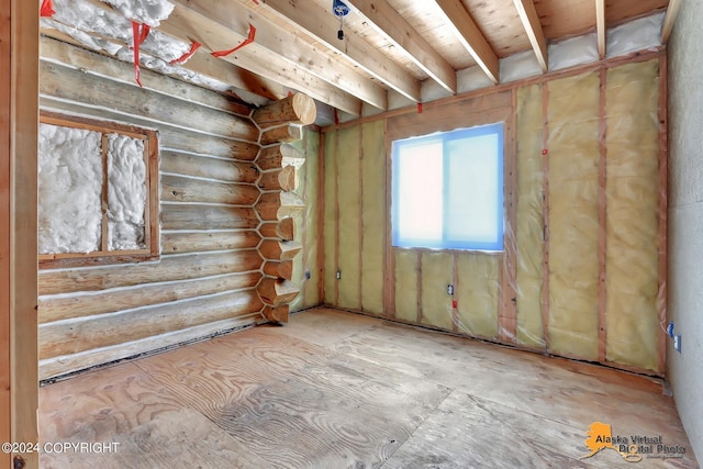 unfurnished room featuring log walls