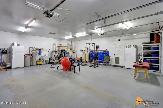 garage featuring white refrigerator and a garage door opener