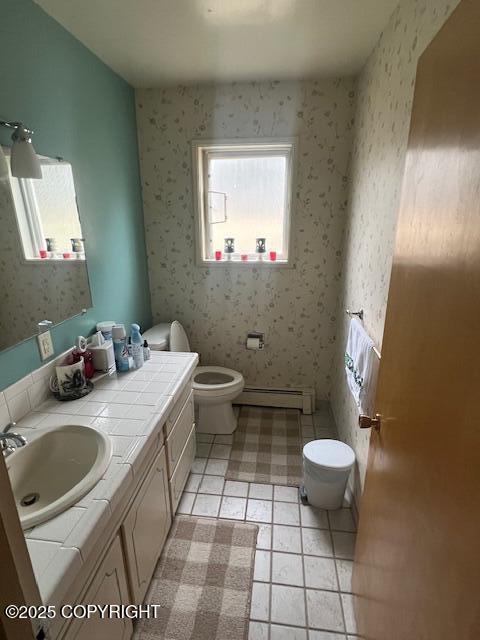 bathroom with vanity, a baseboard heating unit, toilet, and wallpapered walls