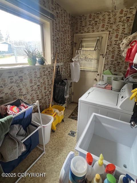 laundry area featuring separate washer and dryer, laundry area, and wallpapered walls