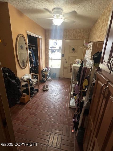miscellaneous room with a ceiling fan, wallpapered walls, and a textured ceiling