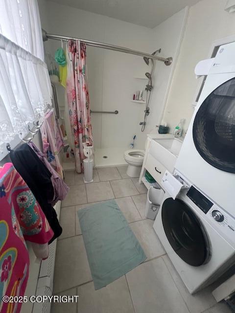 full bath with stacked washer and dryer, toilet, a shower stall, and tile patterned floors