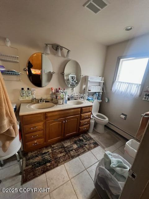 full bath with baseboard heating, a sink, double vanity, toilet, and visible vents