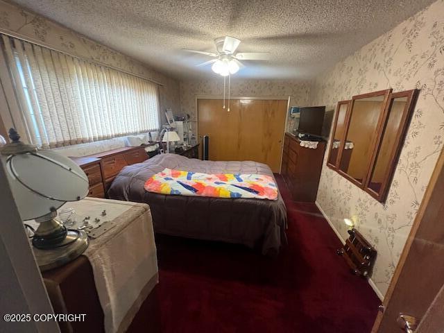 bedroom featuring ceiling fan, wallpapered walls, and a textured ceiling