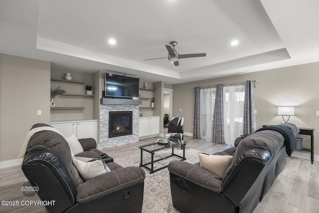 living room with a tray ceiling, light hardwood / wood-style flooring, and a fireplace