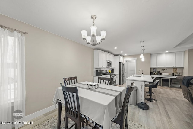 dining room with light hardwood / wood-style floors, sink, and an inviting chandelier