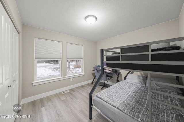 bedroom with a closet, hardwood / wood-style floors, and a textured ceiling