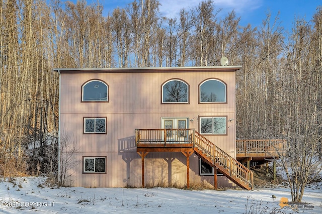 snow covered back of property with a deck