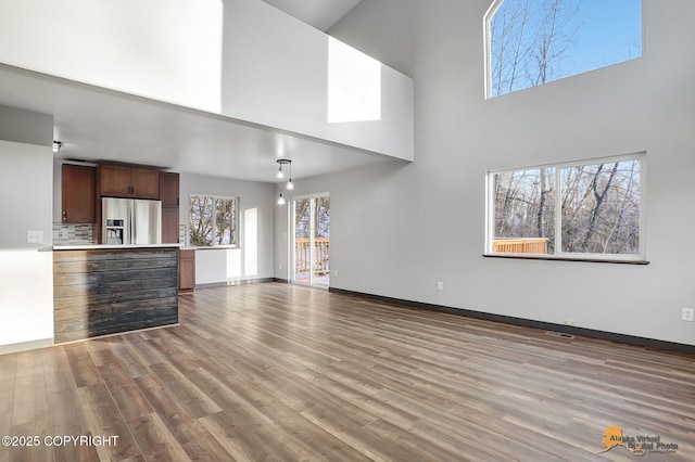 unfurnished living room with a towering ceiling and wood-type flooring