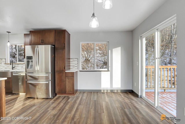 kitchen featuring stainless steel appliances, hardwood / wood-style floors, pendant lighting, and backsplash