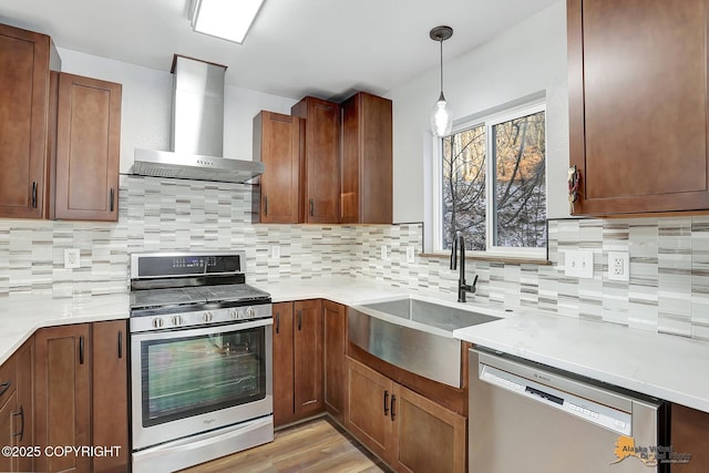 kitchen with sink, appliances with stainless steel finishes, pendant lighting, decorative backsplash, and wall chimney range hood