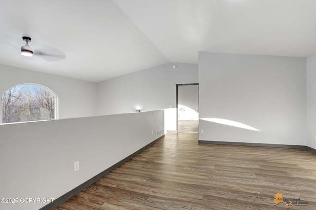 empty room with dark wood-type flooring and vaulted ceiling