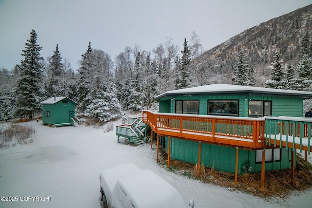 snow covered rear of property with an outbuilding and a deck with mountain view