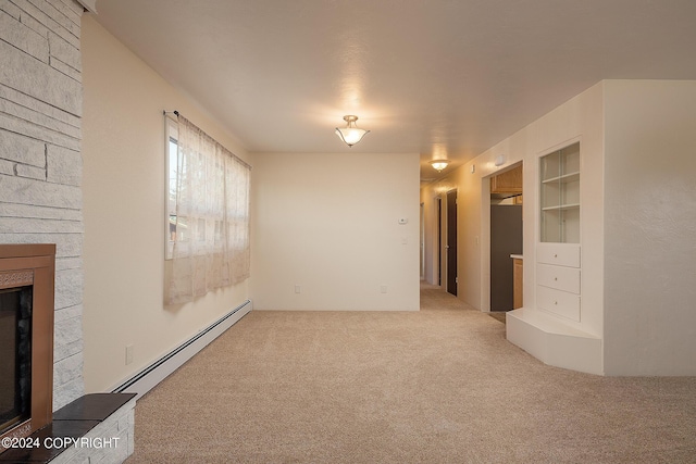 unfurnished living room with carpet flooring, built in shelves, a stone fireplace, and baseboard heating