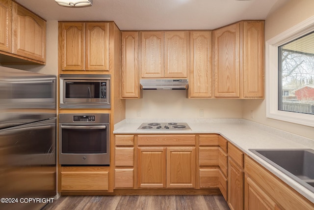 kitchen with stainless steel microwave, dark hardwood / wood-style floors, stovetop, fridge, and light brown cabinetry