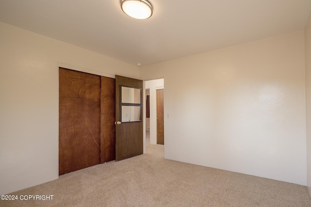 unfurnished bedroom with light carpet and a closet