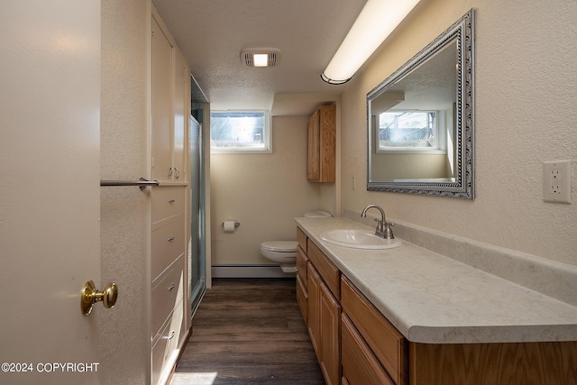 bathroom with a textured ceiling, vanity, baseboard heating, hardwood / wood-style flooring, and toilet