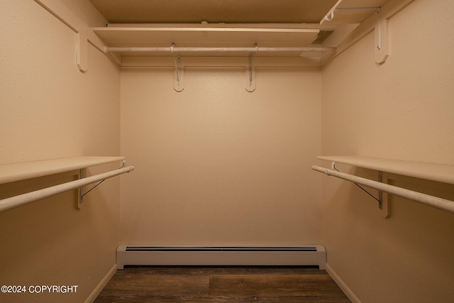 spacious closet featuring dark hardwood / wood-style flooring and a baseboard heating unit