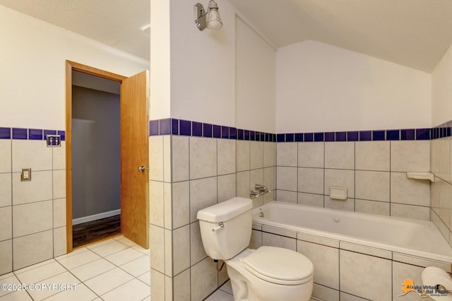 bathroom with tile walls, tile patterned flooring, tiled bath, and toilet