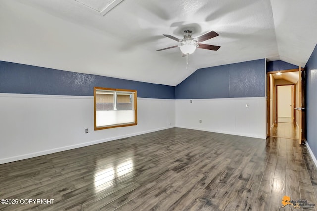 interior space featuring ceiling fan, lofted ceiling, dark hardwood / wood-style floors, and a textured ceiling