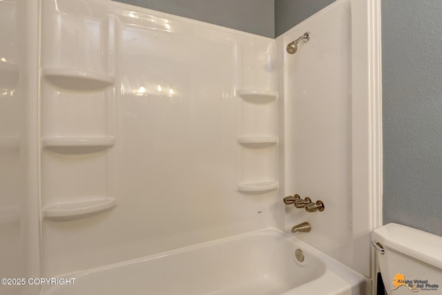 bathroom featuring shower / washtub combination and toilet