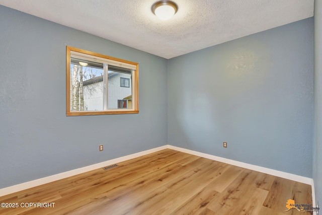 unfurnished room featuring wood-type flooring and a textured ceiling