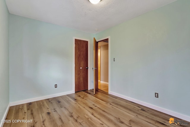 empty room with a textured ceiling and light wood-type flooring