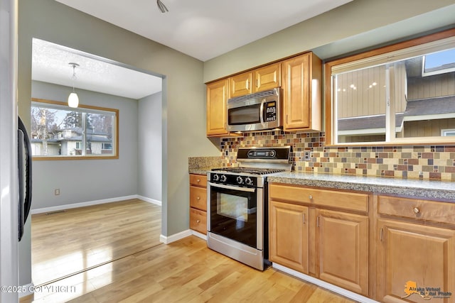 kitchen with stainless steel appliances, decorative light fixtures, light hardwood / wood-style floors, and decorative backsplash