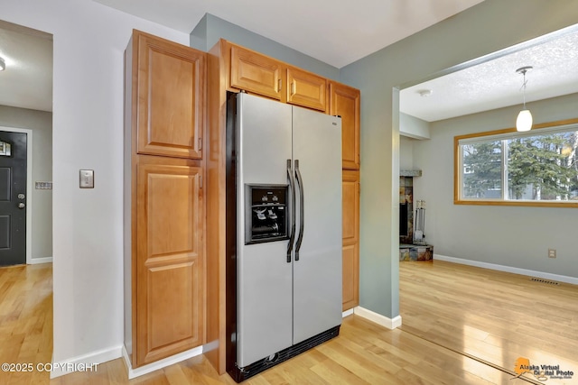 kitchen with pendant lighting, light hardwood / wood-style flooring, and stainless steel refrigerator with ice dispenser