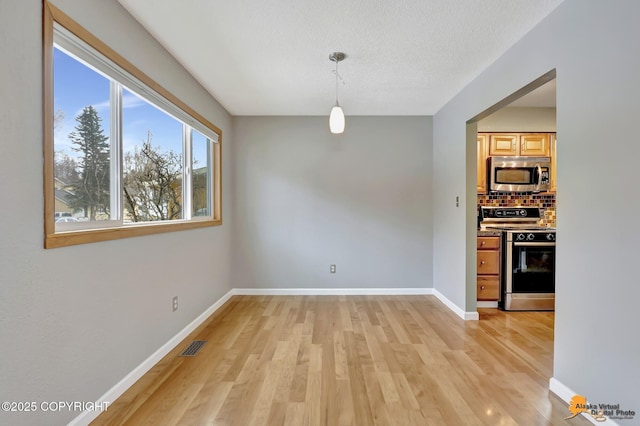 unfurnished dining area featuring light hardwood / wood-style floors and a textured ceiling