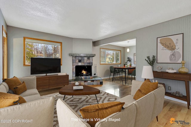 living room with a fireplace, light hardwood / wood-style floors, and a textured ceiling