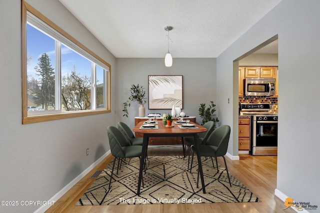 dining room featuring a textured ceiling and light wood-type flooring