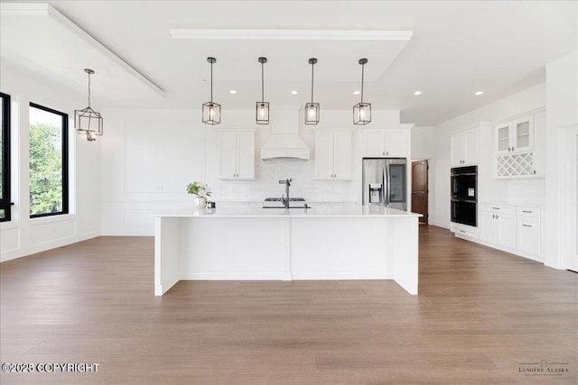1690 W Valley Ridge Dr, Wasilla, AK 99654 - kitchen with stainless steel fridge with ice dispenser, custom range hood, tasteful backsplash, wood finished floors, and recessed lighting