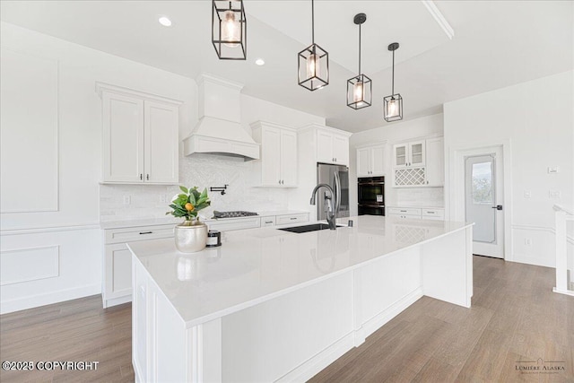 1690 W Valley Ridge Dr, Wasilla, AK 99654 - kitchen featuring a sink, wood finished floors, decorative backsplash, white cabinetry, and a spacious island