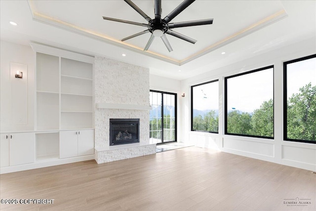 1690 W Valley Ridge Dr, Wasilla, AK 99654 - unfurnished living room featuring a tray ceiling, built in features, light wood finished floors, a ceiling fan, and ornamental molding