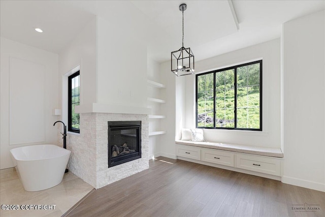 1690 W Valley Ridge Dr, Wasilla, AK 99654 - unfurnished living room with plenty of natural light, a glass covered fireplace, a chandelier, and light wood-style floors