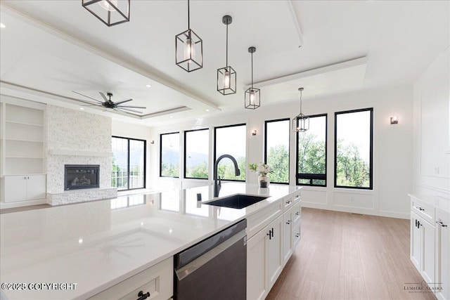 1690 W Valley Ridge Dr, Wasilla, AK 99654 - kitchen featuring dishwashing machine, a sink, a stone fireplace, white cabinetry, and a raised ceiling
