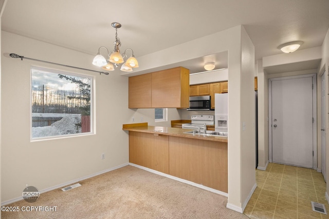 kitchen featuring sink, white electric stove, kitchen peninsula, hanging light fixtures, and a notable chandelier