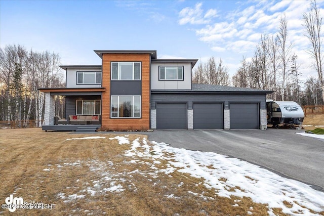 contemporary home with driveway, covered porch, an attached garage, and stone siding