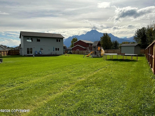 view of yard with a playground, a mountain view, a trampoline, and a storage unit