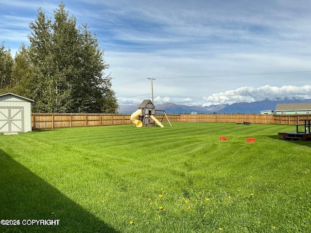 view of yard featuring a playground, a shed, and a mountain view