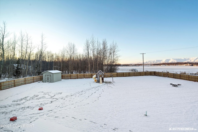 snowy yard with a water and mountain view and a storage unit