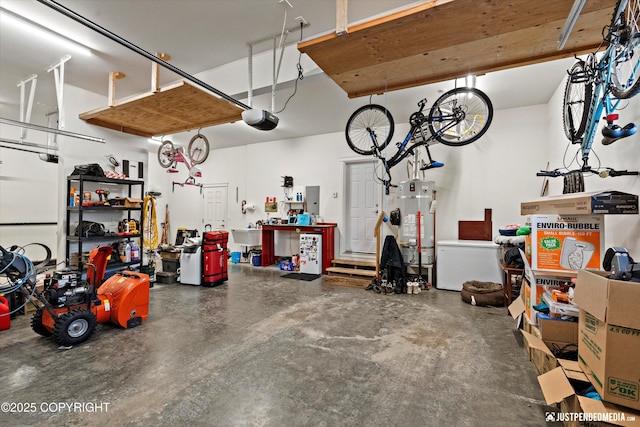 garage featuring strapped water heater, a garage door opener, a workshop area, and sink