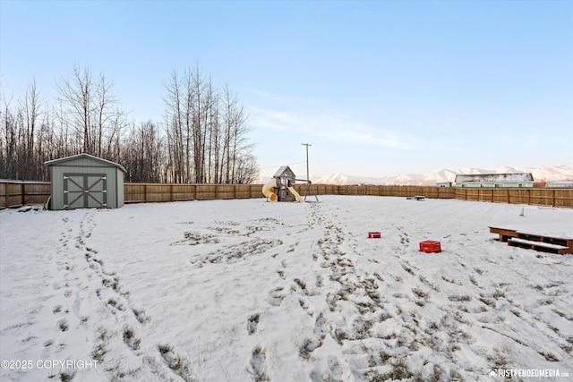 snowy yard with a mountain view and a storage unit