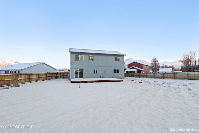 snow covered rear of property featuring a deck with mountain view