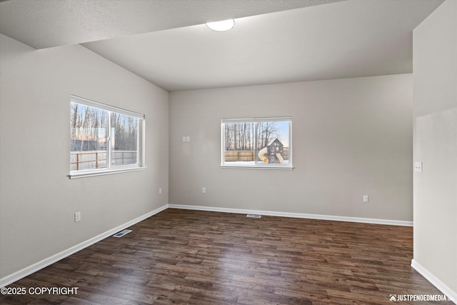 empty room with dark hardwood / wood-style floors and a healthy amount of sunlight