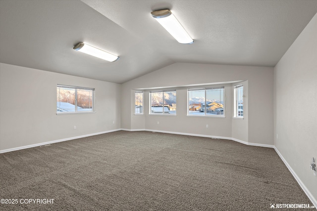 unfurnished room featuring dark carpet, vaulted ceiling, and a textured ceiling