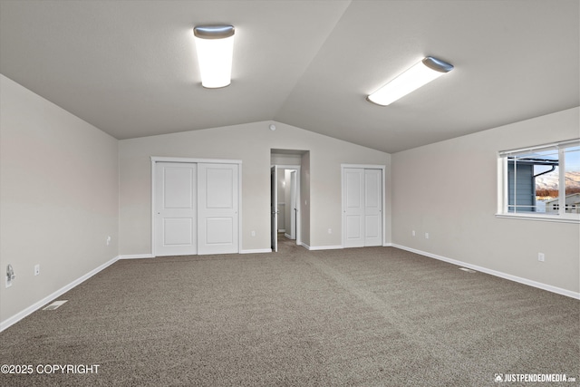 interior space with vaulted ceiling, carpet flooring, and two closets