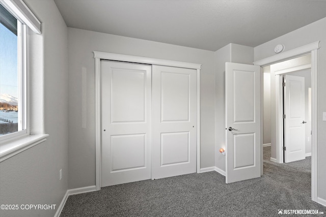 unfurnished bedroom with a closet and dark colored carpet