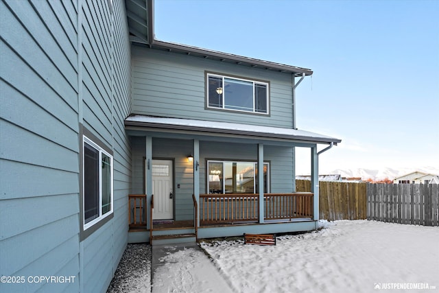 snow covered back of property featuring a porch